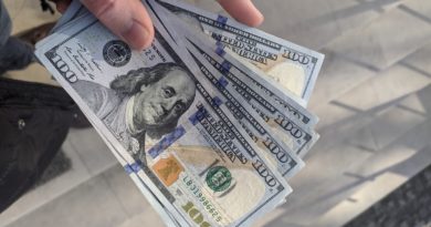 Un homme tenant des billets de 100 Dollars en main.